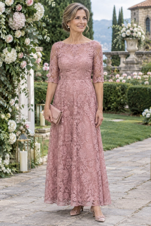A woman wears a dusty rose lace dress with elbow-length sleeves, a matching clutch, and pale pink heels.