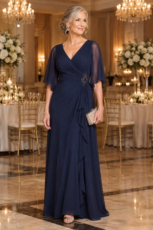A floor-length navy gown with a wrap-style neckline, sheer flutter sleeves, and a jeweled waist detail, styled with a metallic clutch and sandals.
