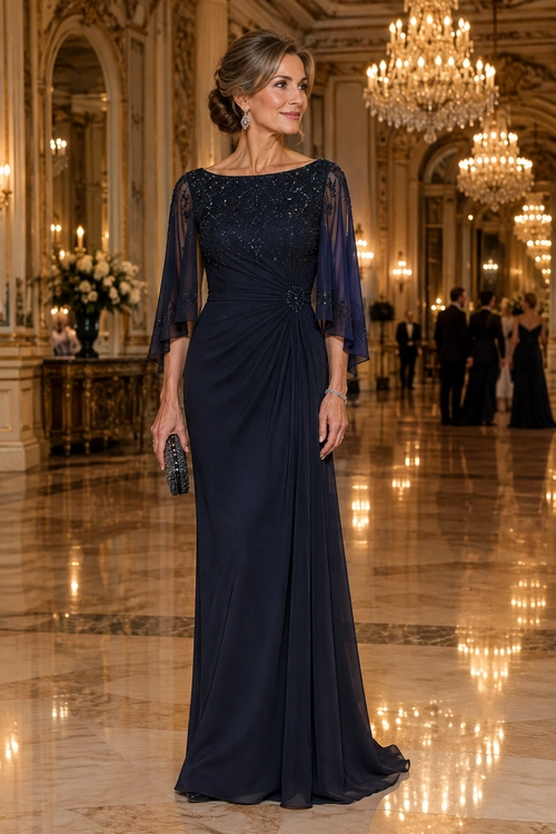 Navy Embellished Evening Gown A woman wears a floor-length navy gown with a beaded bodice, sheer cape sleeves, and a draped waist, accessorized with a small clutch, earrings, and a bracelet.