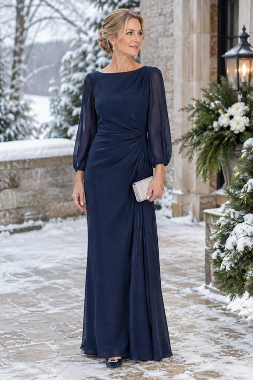 A woman wears a floor-length navy gown with sheer sleeves and waist draping, holding a silver clutch.