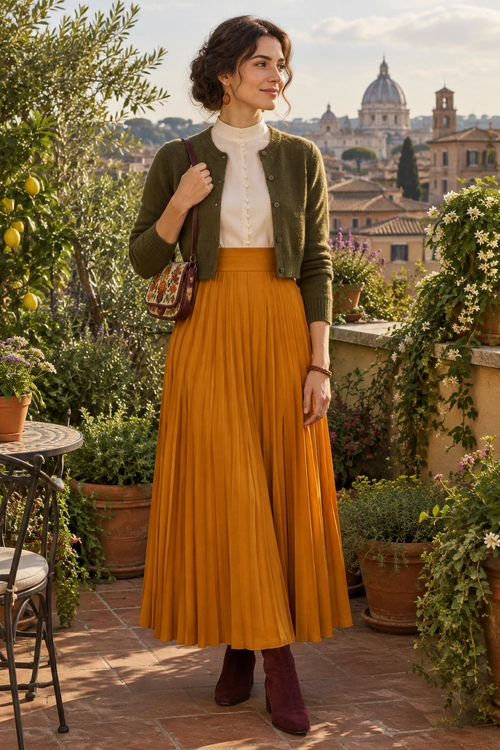Olive Cardigan and Mustard Pleated Skirt Outfit A woman wears an olive cropped cardigan over a cream high-neck blouse with a mustard pleated skirt, burgundy ankle boots, and a patterned shoulder bag.
