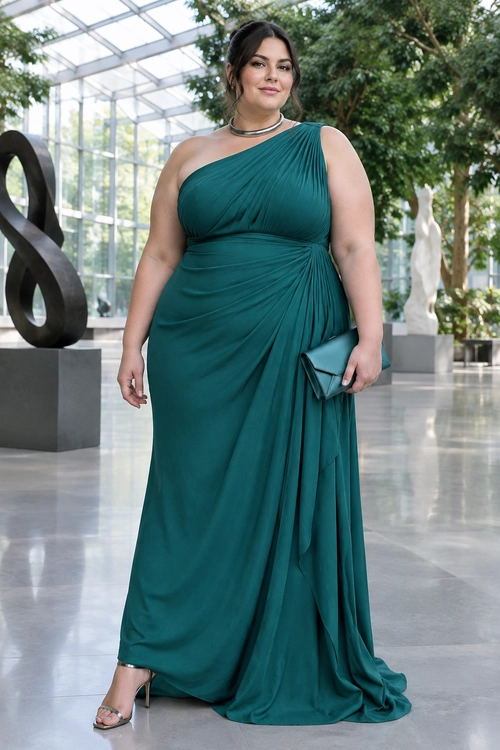 A woman wears a floor-length teal satin one-shoulder gown with gold earrings and holds a small gold clutch.